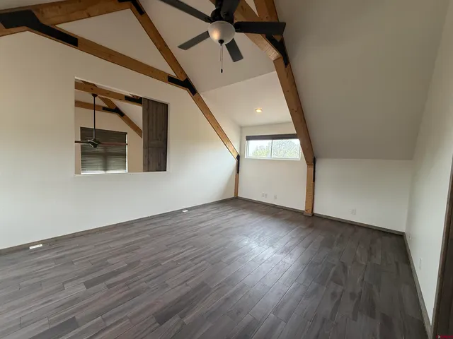 an empty room with wooden floor cabinet and windows