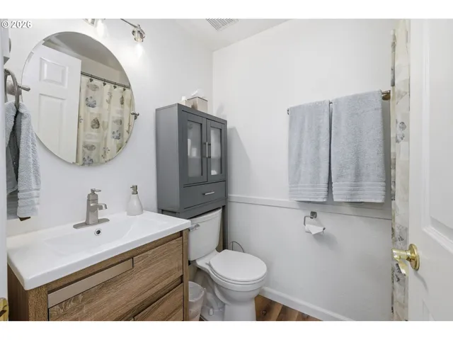 a view of a hallway with wooden floor and a refrigerator