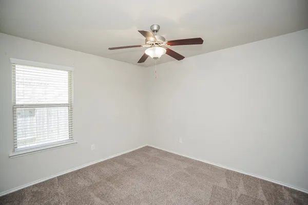 an empty room with ceiling fan and window