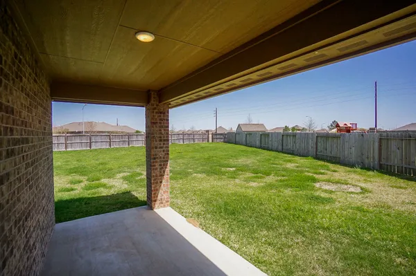 a view of a backyard with brick wall and plants