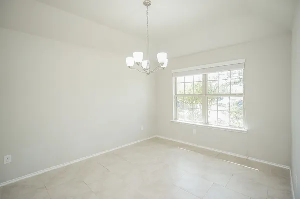 an empty room with windows and chandelier fan