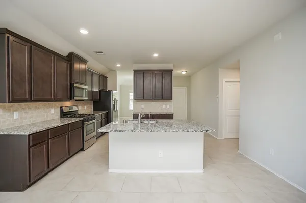 a kitchen with kitchen island granite countertop a sink counter top space appliances and cabinets