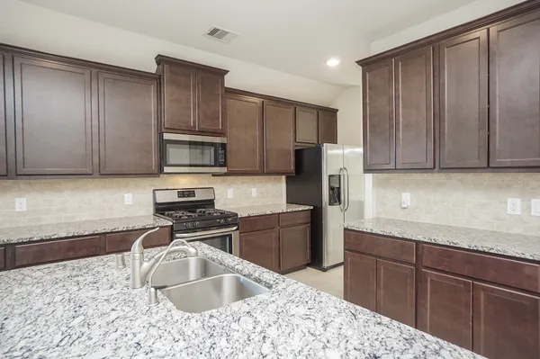 a kitchen with granite countertop stainless steel appliances a sink stove and cabinets