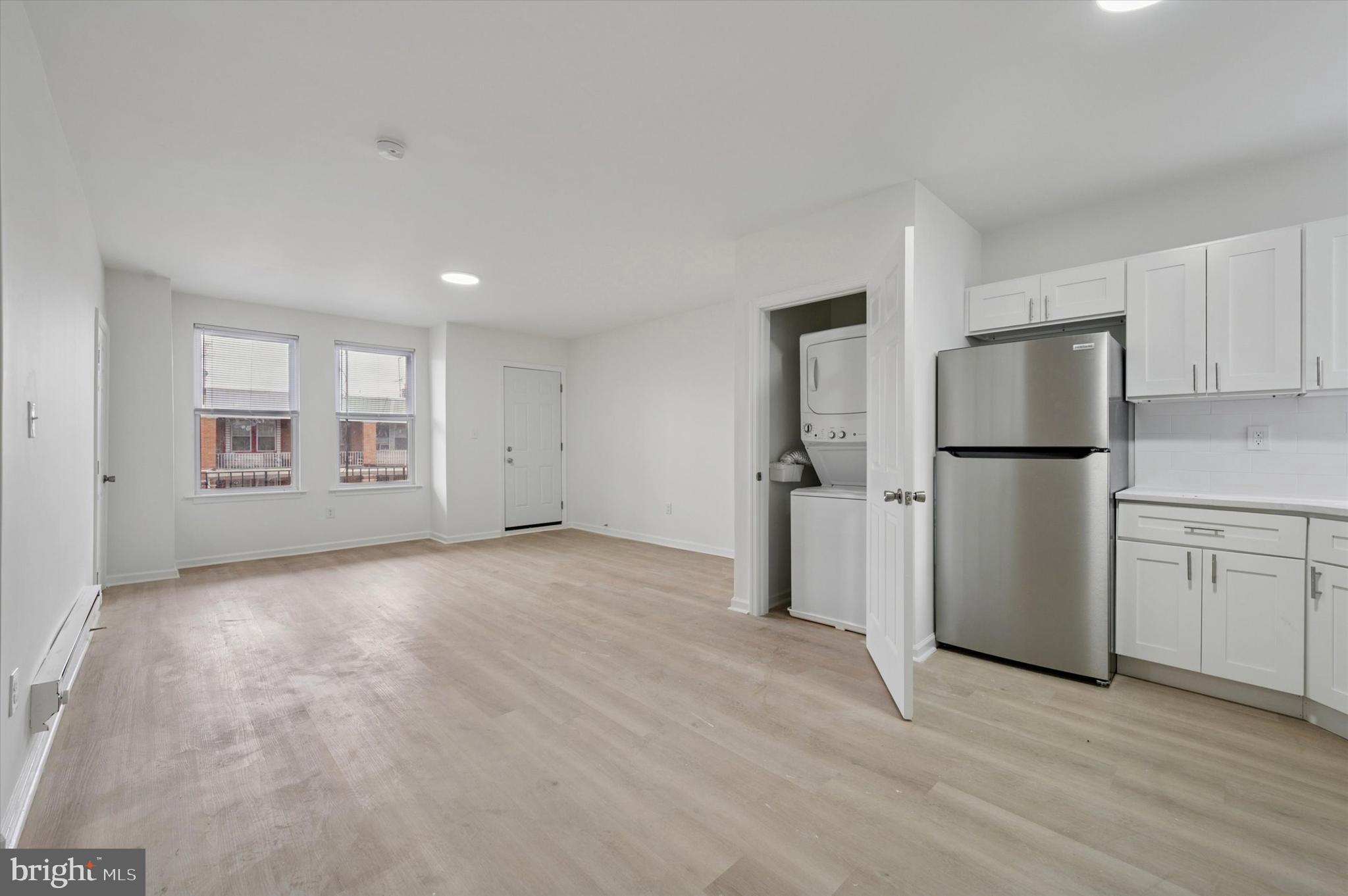 a view of empty room with a kitchen and a refrigerator
