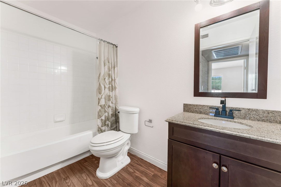 1901 Rio Canyon Court, Unit 102 Las Vegas, NV 89128 - Photo 16 of 23 A well-appointed bathroom features a practical vanity with a granite countertop and rich wood cabinetry.