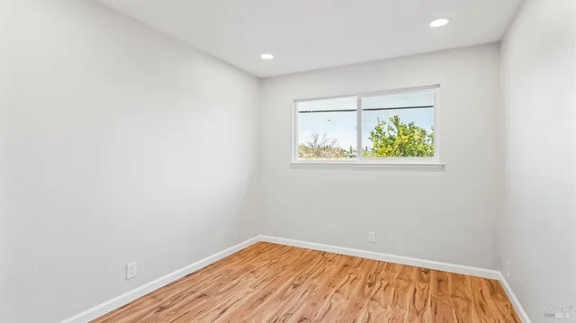 an empty room with wooden floor and window