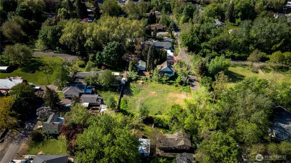 an aerial view of a residential houses with outdoor space and trees all around