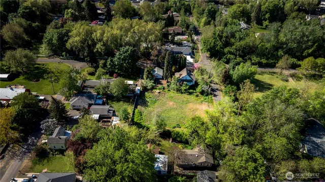 an aerial view of a residential houses with outdoor space and trees all around