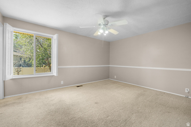 2088 Falcon Way Sandy, UT 84093 - Photo 22 of 46 Spacious room featuring neutral carpeting, light beige walls, white chair rail molding, a large window with white plantation shutters, and a ceiling fan with integrated lighting