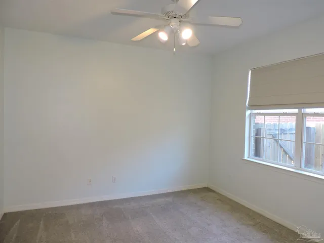 an empty room with a window and chandelier fan