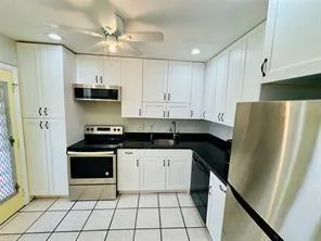 a kitchen with granite countertop a refrigerator sink and cabinets