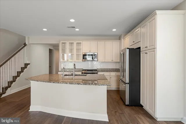a kitchen with kitchen island stainless steel appliances a refrigerator a stove top oven and wooden floors
