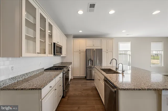 a kitchen with granite countertop stainless steel appliances a sink stove and refrigerator