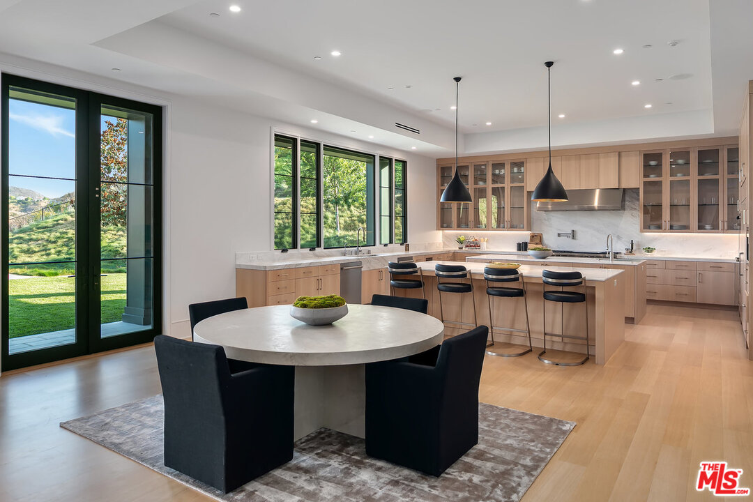 25211 Jim Bridger Road Hidden Hills, CA 91302 - Photo 14 of 42 a kitchen with stainless steel appliances granite countertop a stove a sink a microwave a dining table and chairs