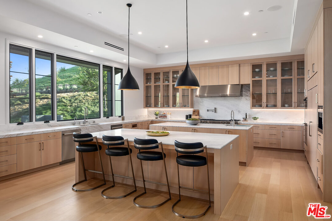 25211 Jim Bridger Road Hidden Hills, CA 91302 - Photo 15 of 42 a kitchen with a table chairs stove and cabinets