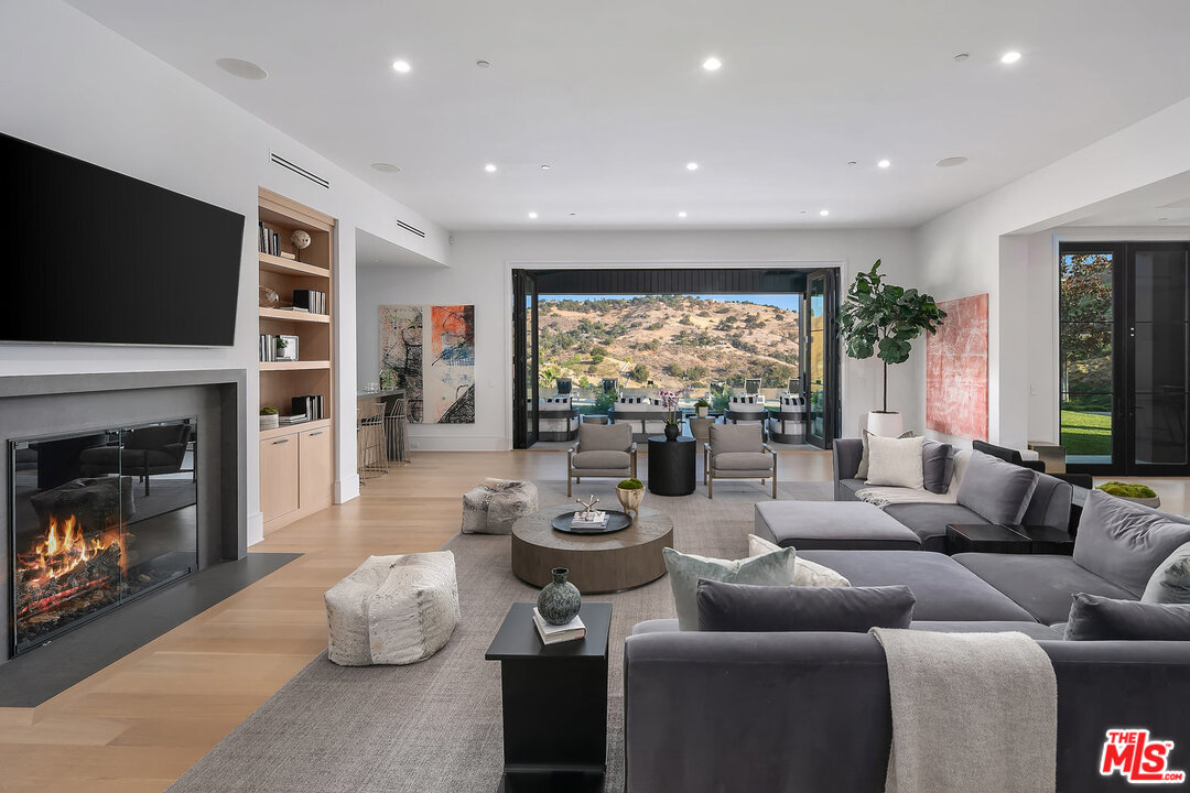 25211 Jim Bridger Road Hidden Hills, CA 91302 - Photo 19 of 42 a living room with furniture flat screen tv and a fireplace
