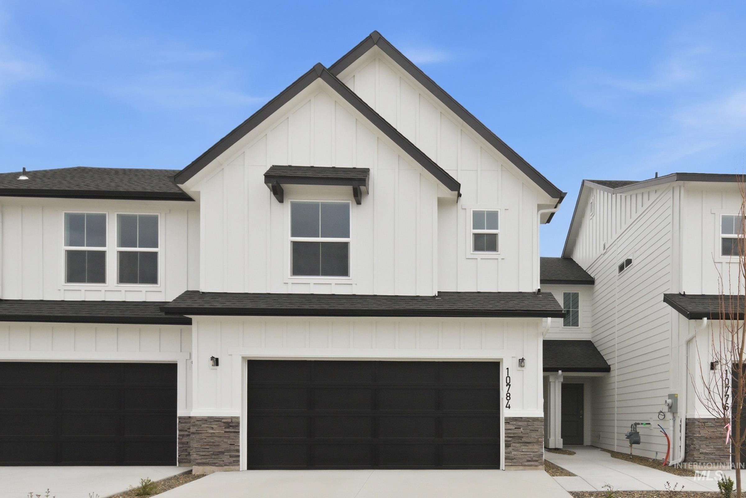 Modern farmhouse style home featuring board and batten siding, roof with shingles, and a garage