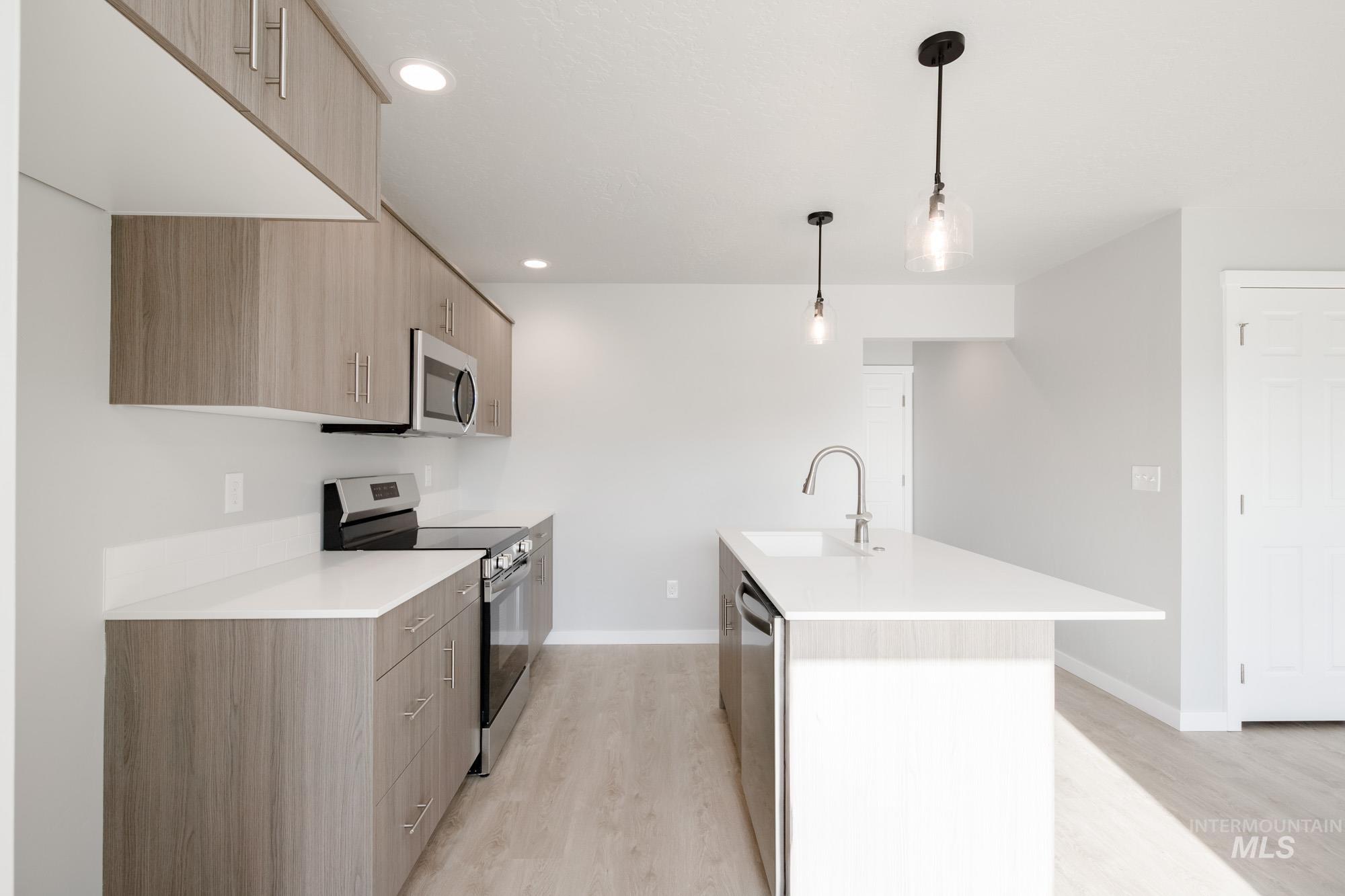 10784 Rutland Street Caldwell, ID 83605 - Photo 5 of 22 Kitchen featuring stainless steel appliances, modern cabinets, hanging light fixtures, and light wood-style flooring