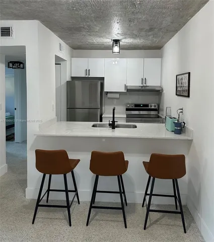 a kitchen with stainless steel appliances a dining table chairs and a refrigerator