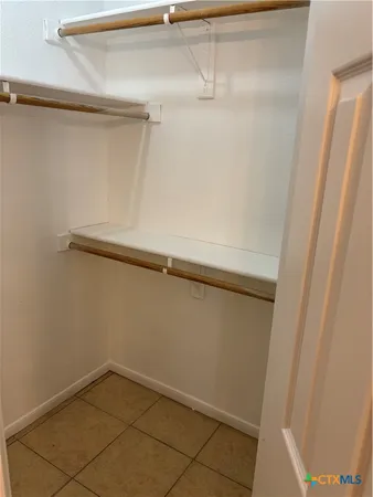 an empty room with chandelier fan and window