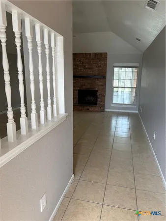 a view of an empty room with a fireplace and a window