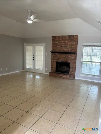an empty room with windows and fireplace