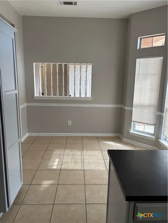 a view of a refrigerator in kitchen and an empty room