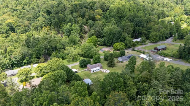 an aerial view of residential house with outdoor space and trees all around