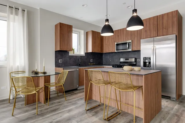 a kitchen with stainless steel appliances granite countertop a stove top oven a sink a dining table and chairs with wooden floor