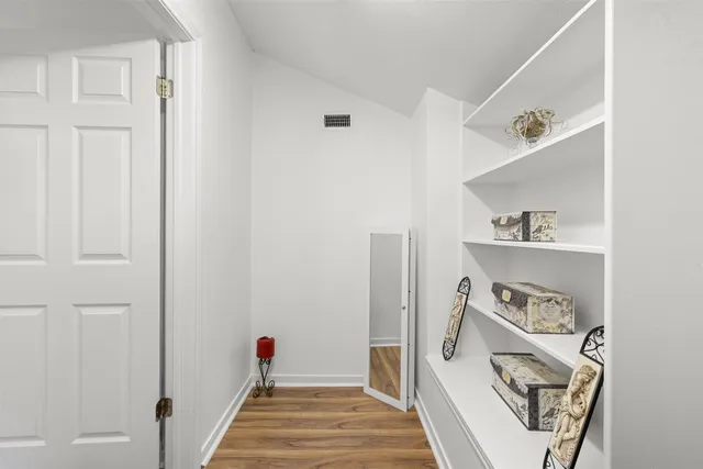 a hallway with white cabinets and wooden floor