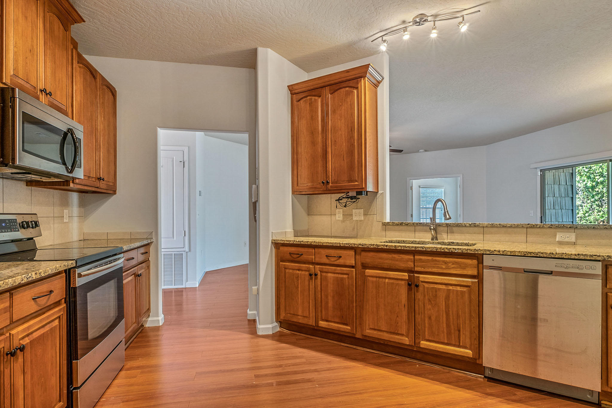 4592 Hermosa Road Crestview, FL 32539 - Photo 11 of 32 a kitchen with stainless steel appliances granite countertop a stove a sink dishwasher and a microwave oven with wooden floor