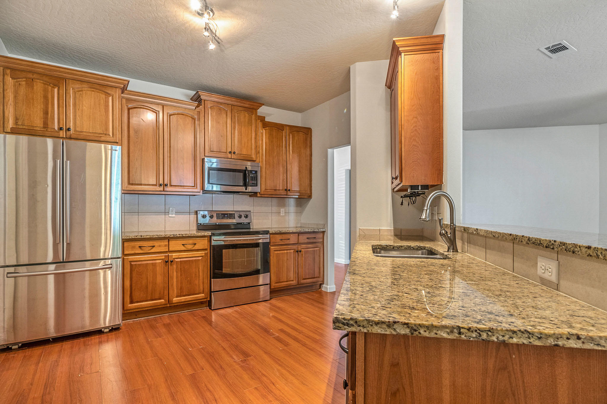 4592 Hermosa Road Crestview, FL 32539 - Photo 12 of 32 a kitchen with stainless steel appliances granite countertop a refrigerator microwave and stove top oven