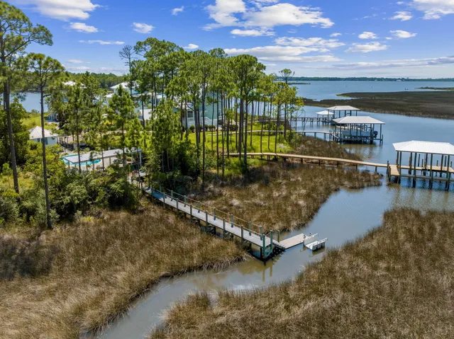 a view of a pathway both side of building with yard and large trees