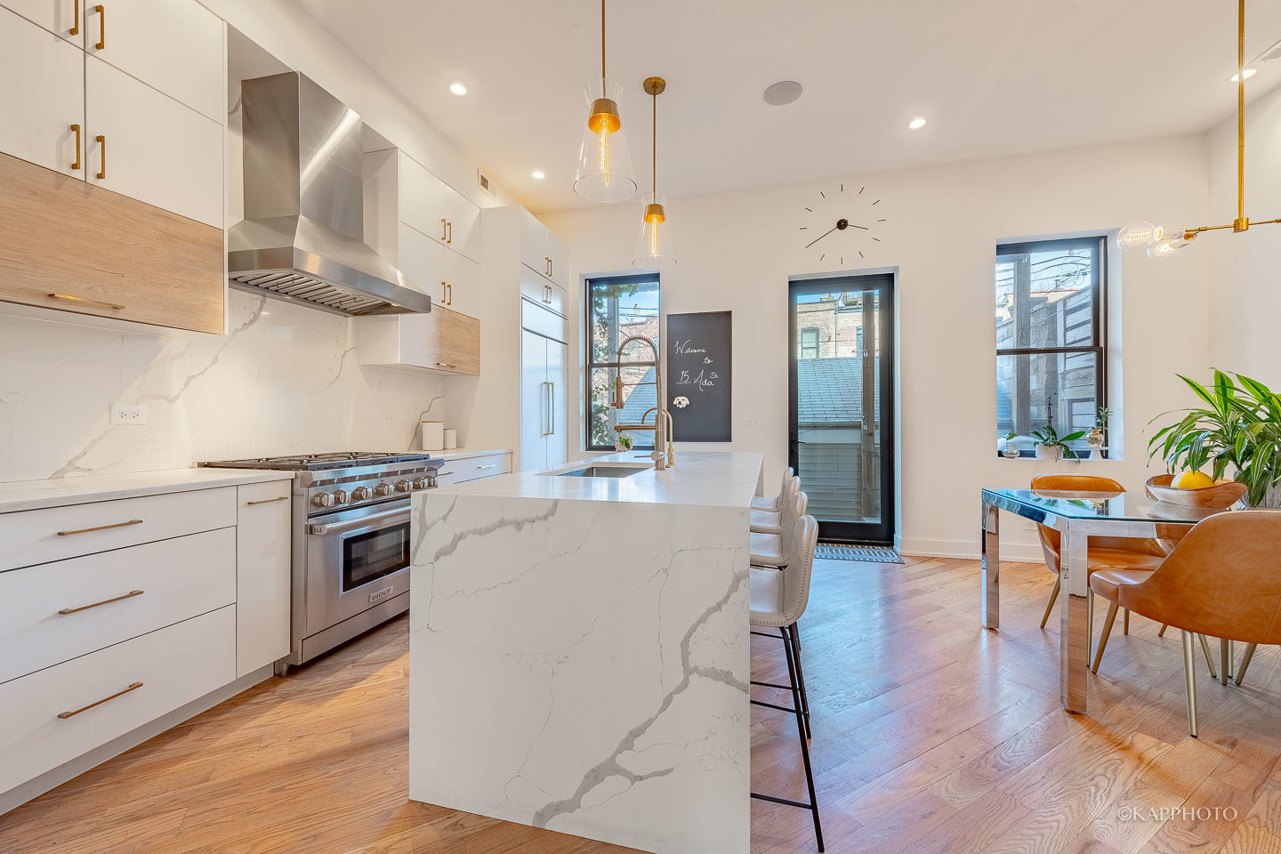 15 North Ada Street Chicago, IL 60607 - Photo 8 of 41 a large kitchen with stainless steel appliances kitchen island granite countertop a stove a sink a refrigerator and a dining table with wooden floor