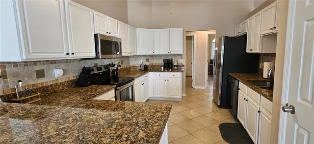 a kitchen with granite countertop a refrigerator stove and sink