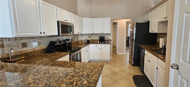 a kitchen with granite countertop a refrigerator a stove a sink a dining table and chairs