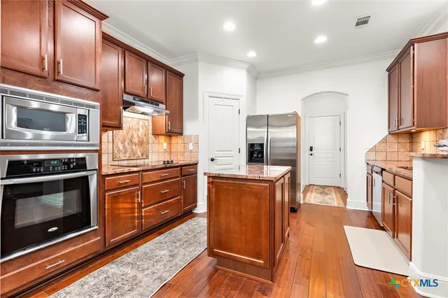 a kitchen with stainless steel appliances granite countertop a sink and a refrigerator