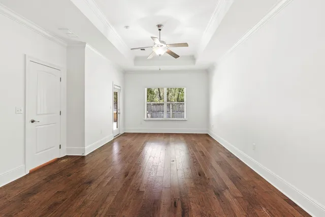 an empty room with wooden floor chandelier fan and windows