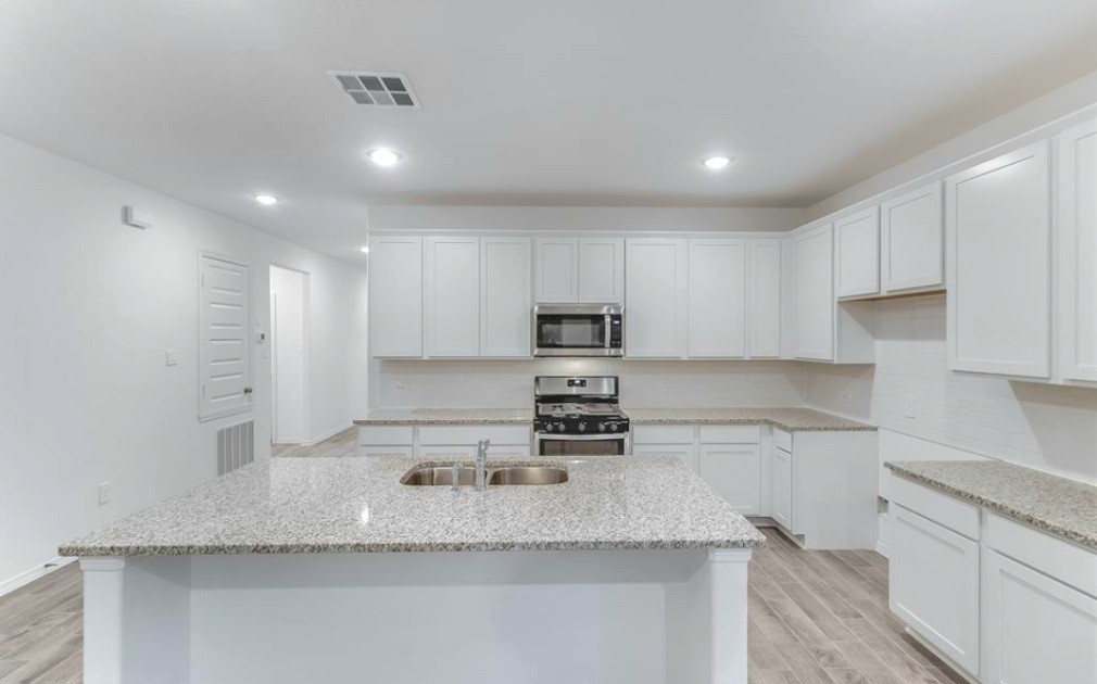 14423 Sunny Bend Way Conroe, TX 77303 - Photo 2 of 9 a kitchen with stainless steel appliances granite countertop a sink a stove and a refrigerator