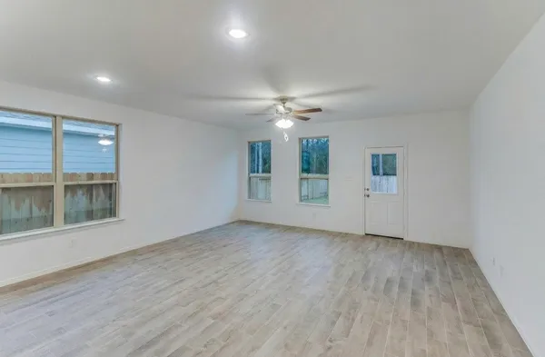 a view of an empty room with a window and wooden floor