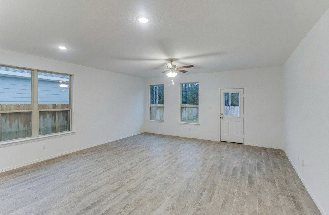 14423 Sunny Bend Way Conroe, TX 77303 - Photo 4 of 9 a view of an empty room with a window and wooden floor