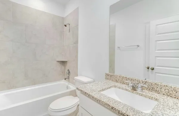 a bathroom with a granite countertop sink toilet a mirror and bathtub
