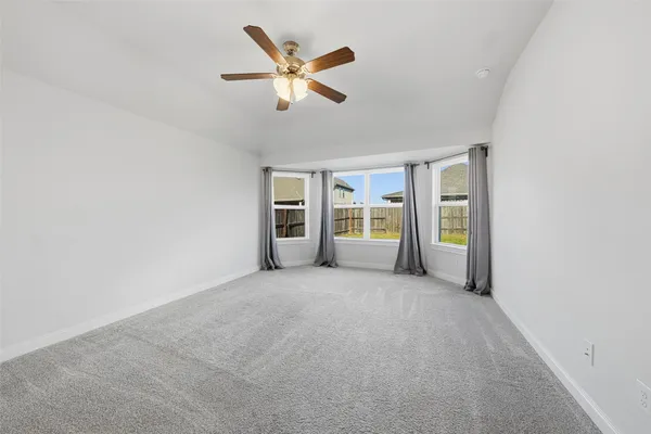 an empty room with chandelier fan and windows