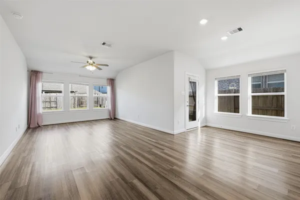 a view of an empty room with wooden floor and windows