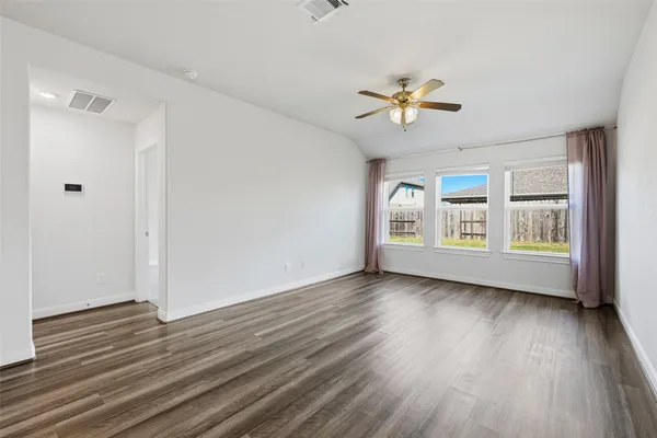 a view of an empty room with a window and wooden floor