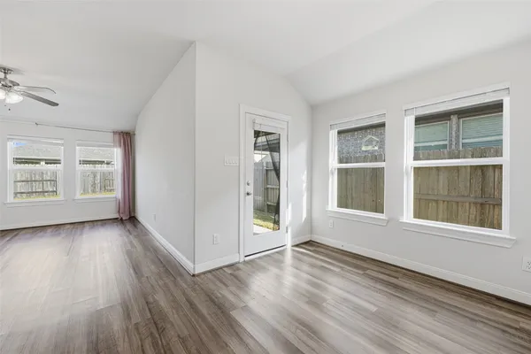 an empty room with wooden floor and windows