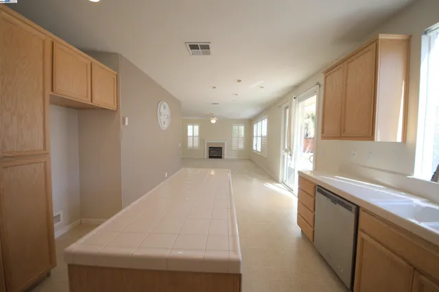 a large white kitchen with a large window a sink and a clock