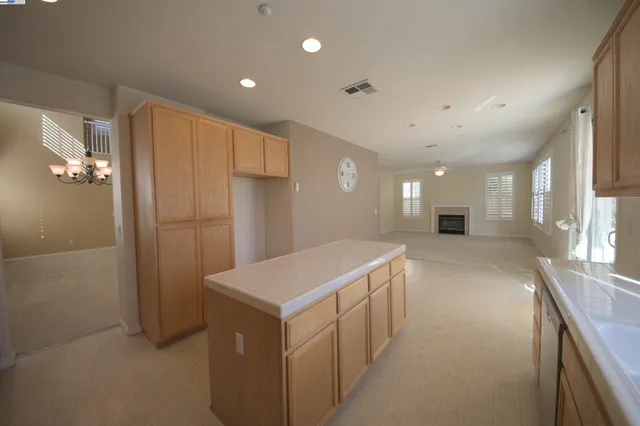 a view of a livingroom with a fireplace a ceiling fan and windows