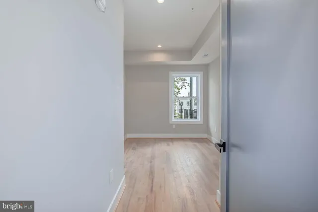 a view of hallway with a window and wooden floor