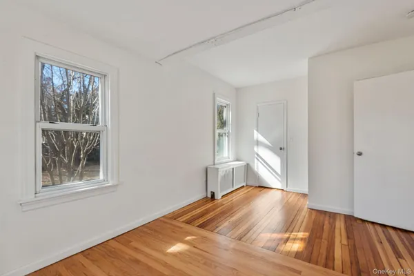 a bedroom with wooden floor and a window